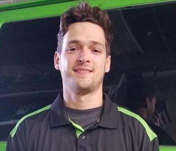 Person with brown hair standing in front of green truck