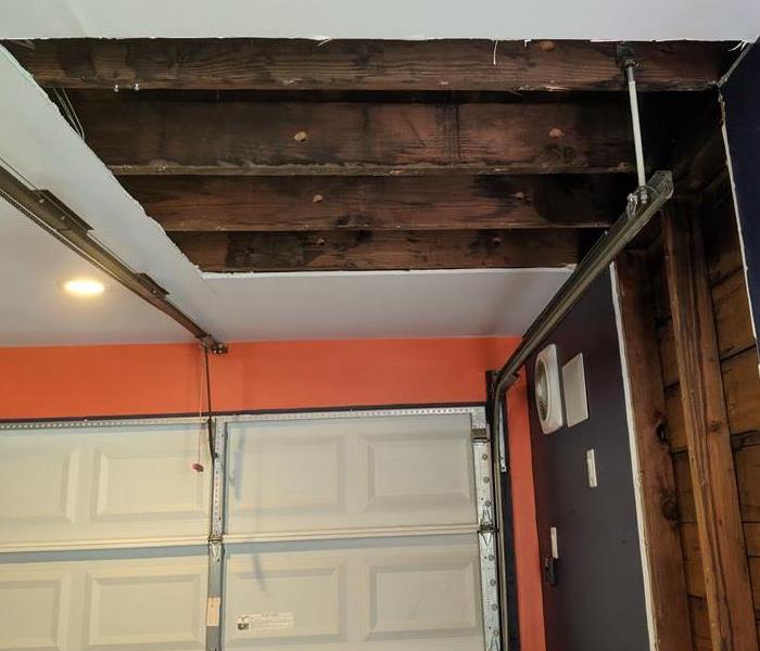 garage with a portion of the water damaged ceiling removed for repair