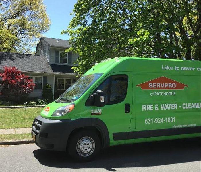Green SERVPRO vehicle outside a residence.