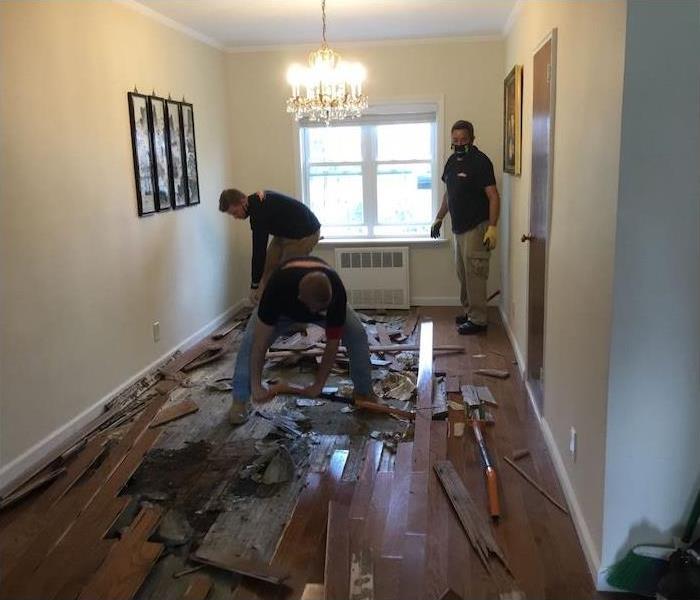 employees removing a water damaged hardwood floor