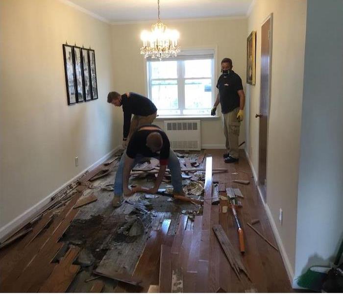 employees removing a water damaged hardwood floor