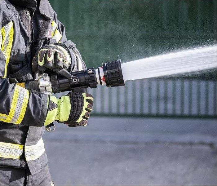 closeup of fireman holding fire hose, hose spewing water