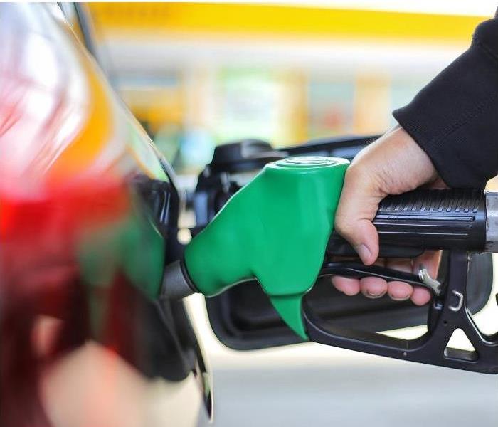 hand holding gas nozzle while pumping gas into car
